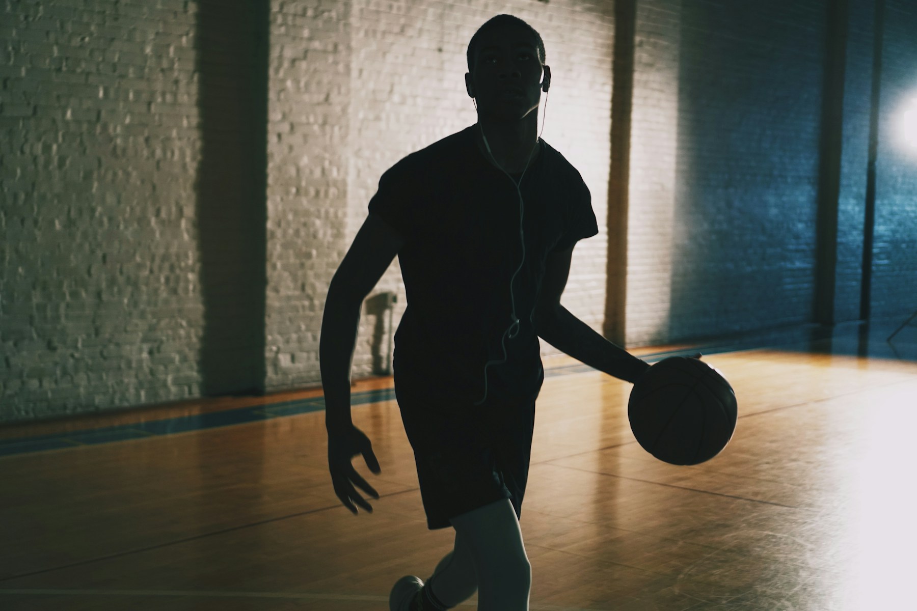 Kapalı basketbol sahasında top süren sporcu